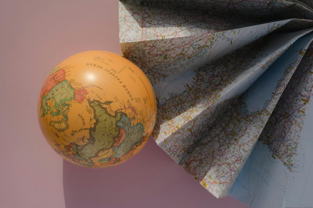 globe by world map on pink paper