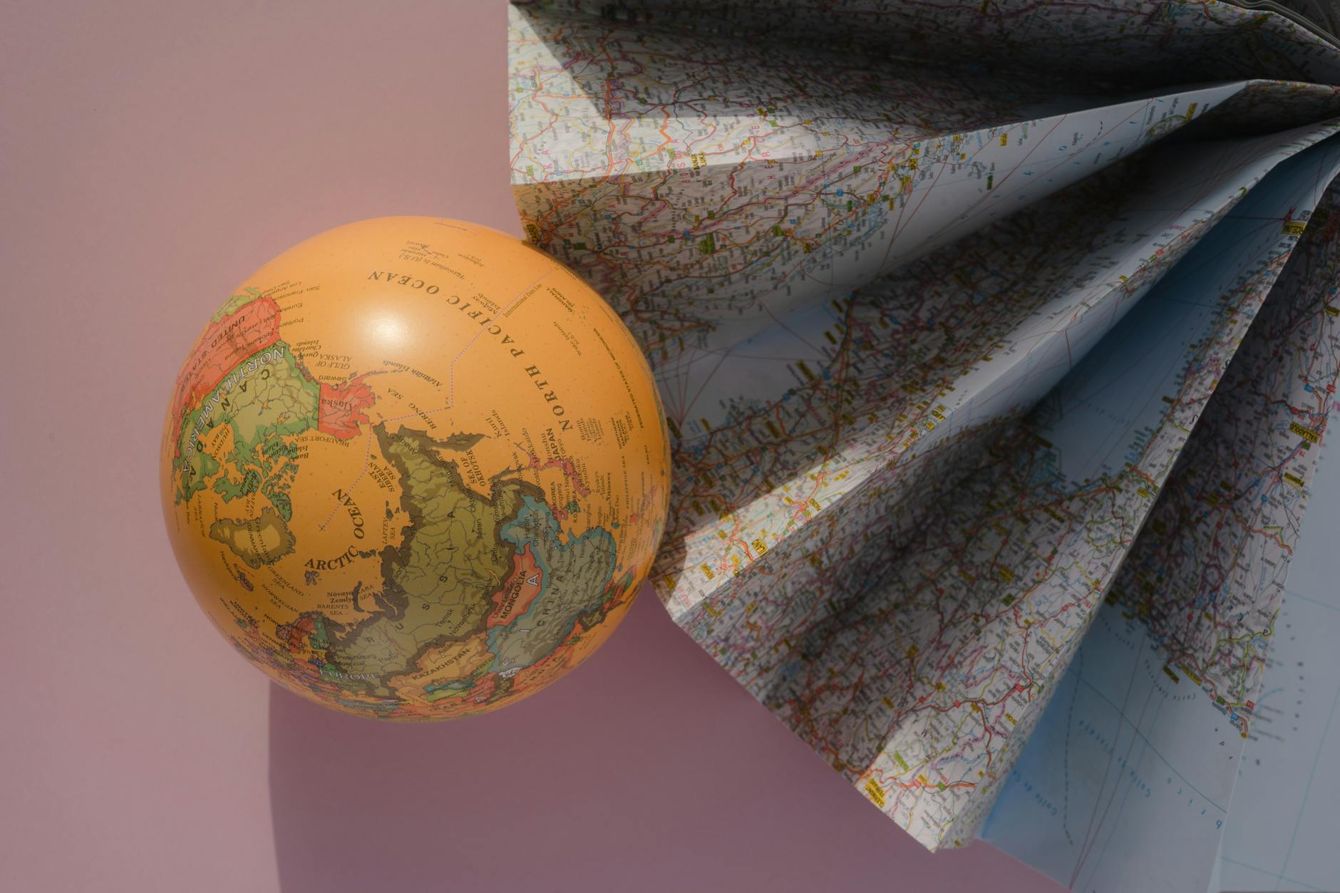 globe by world map on pink paper